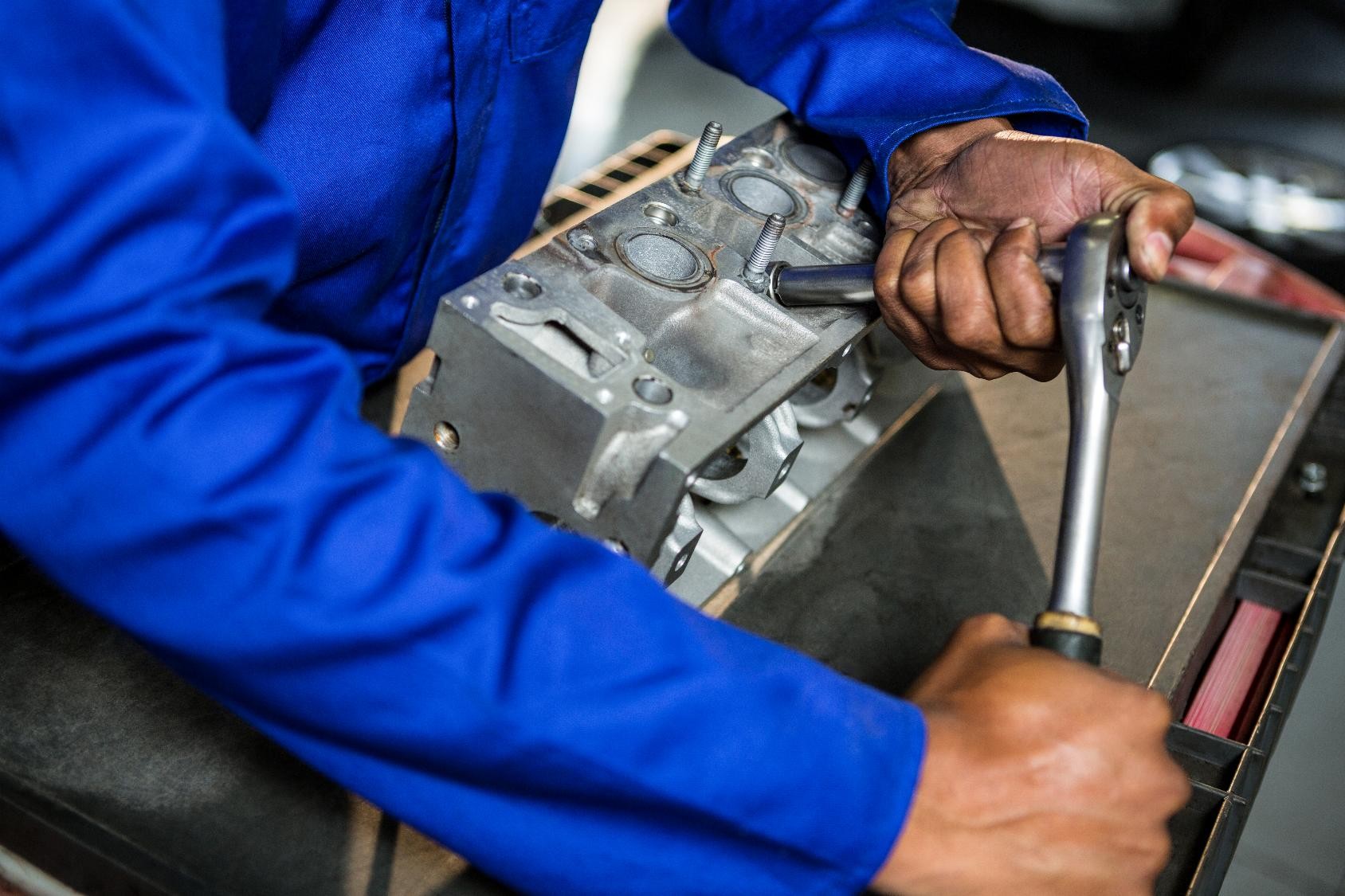 Mechanic in blue uniform using wrench